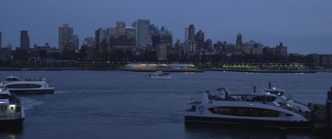 City skyline next to the river with boats floating on water at dusk