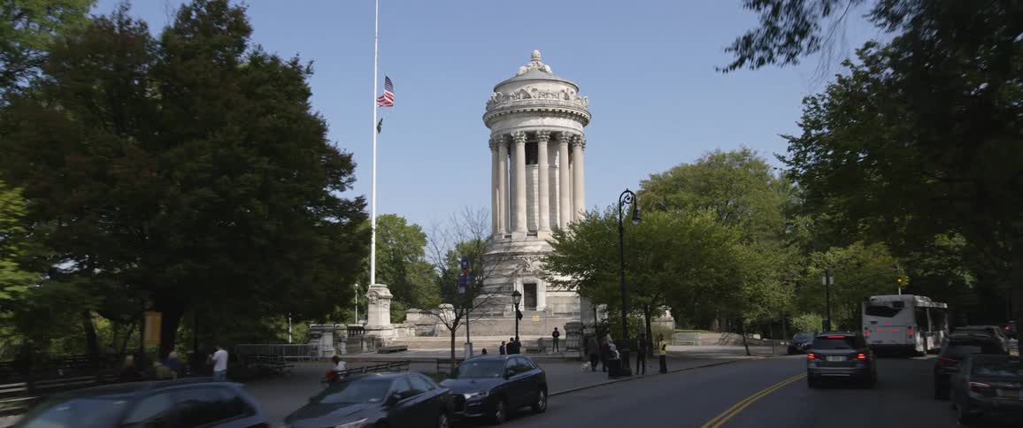 A large stone monument with stairs and a door is beside a busy road