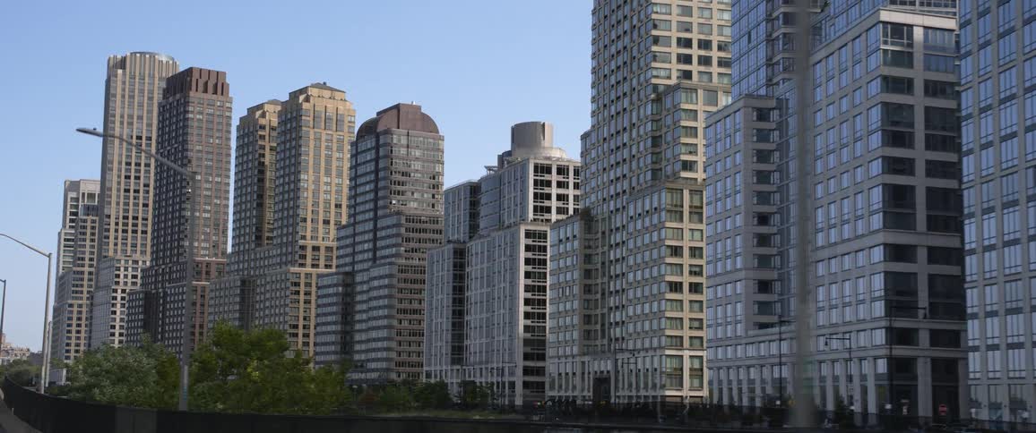 A row of gray skyscrapers along a waterway in a metropolis during the day