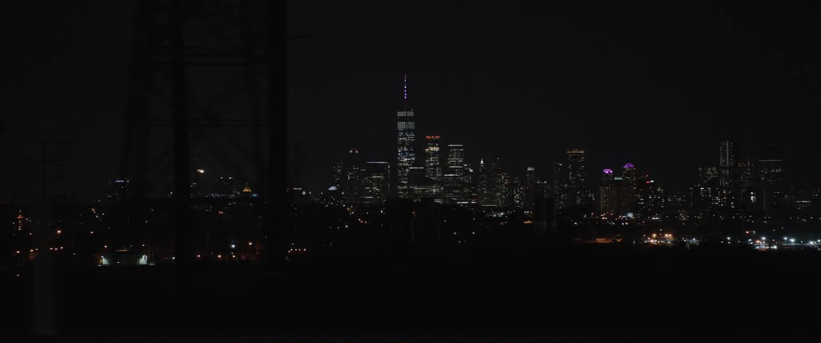 A view of a city skyline at night from a bridge with traffic