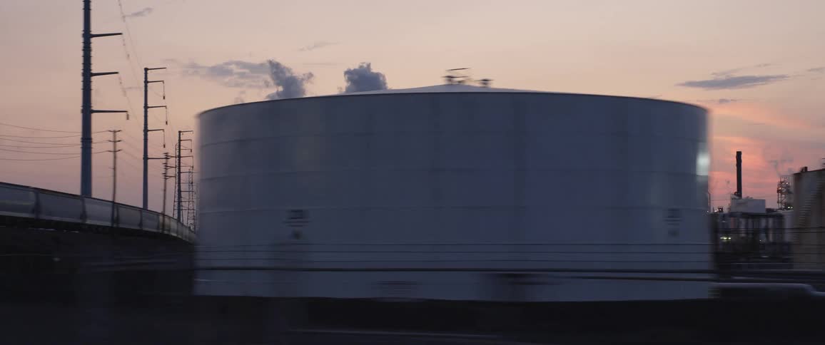 Smoke out of a factory chimney in the horizon of an industrial complex at sunset