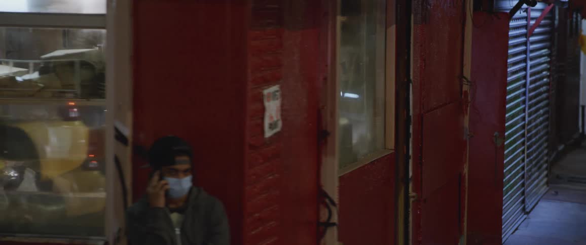 Storefront with red walls and glass doors on a street with people standing and walking outside at night