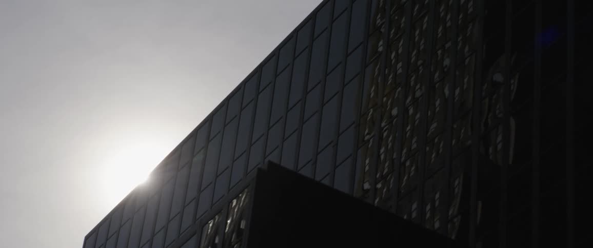 Close up shot of a large office building with the sun behind it