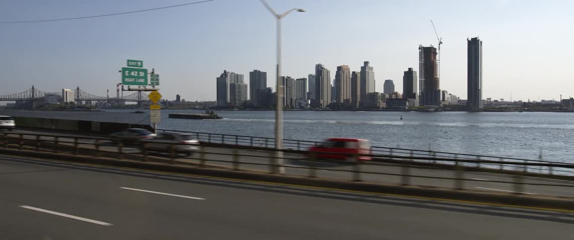 Skyline of new york city in front of a river filmed from the highway at morning