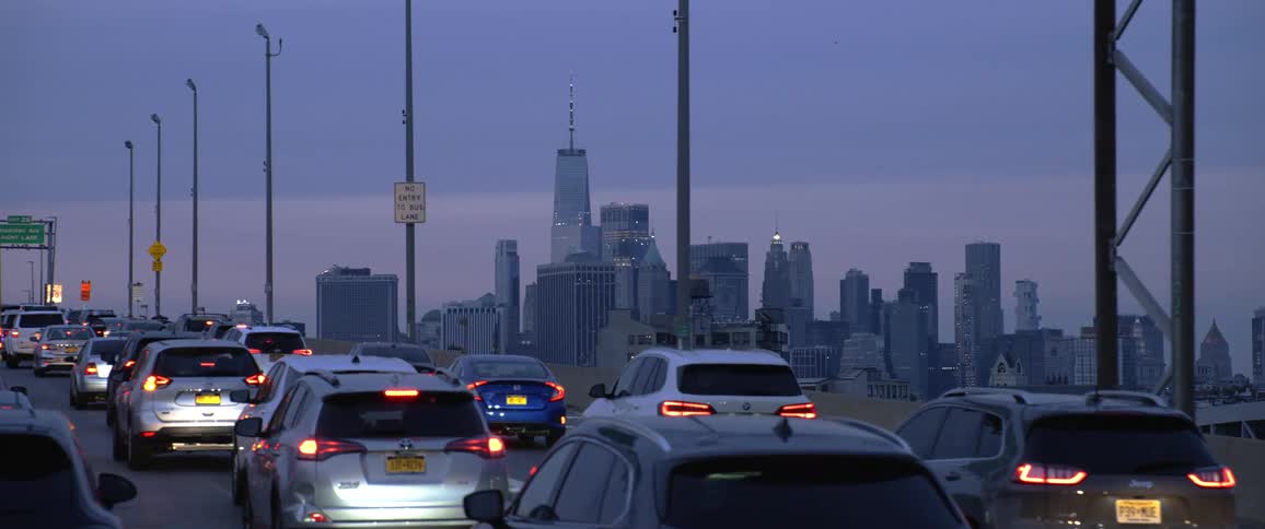 A freeway with a lot og trafic with vehicles in front of a city skyline