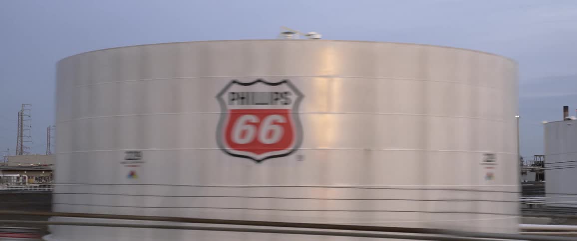 Gas station and stopped train border refinery and associated tanks