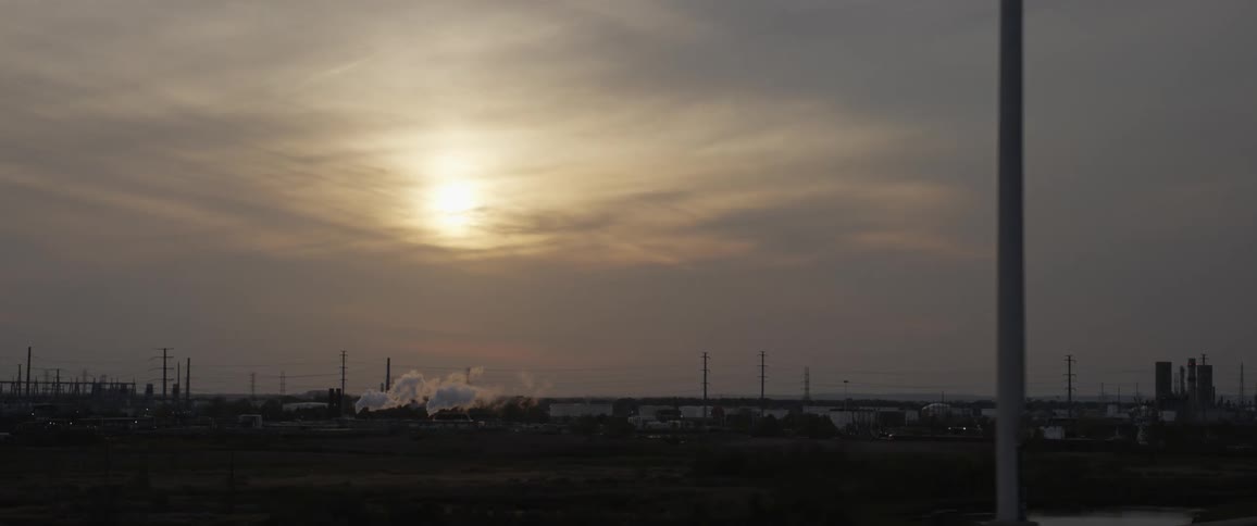 Smoke billowing out of a factory as the sun sets