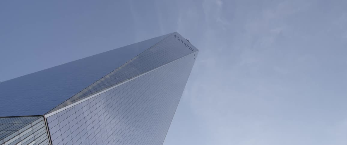 The facade of a skyscraper reflects the blue daytime sky