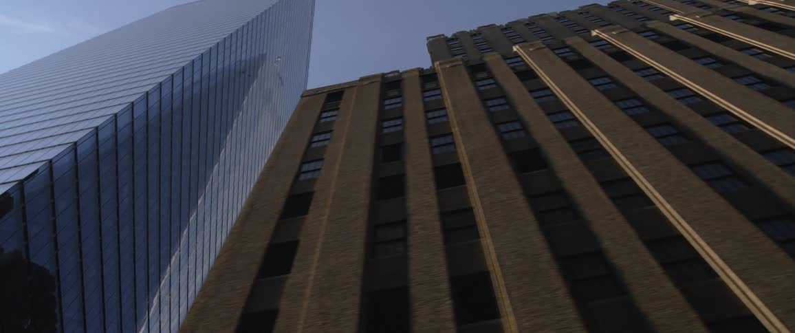 Looking up the side of a brown skyscraper among other tall buildings