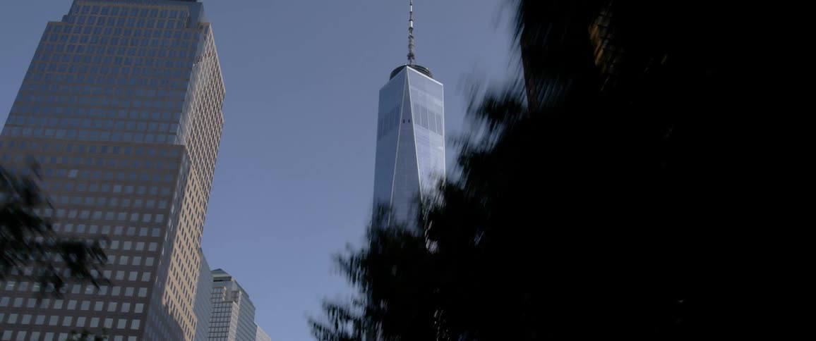A tall skyscrapers looms over the other buildings of a metropolis under a clear blue sky