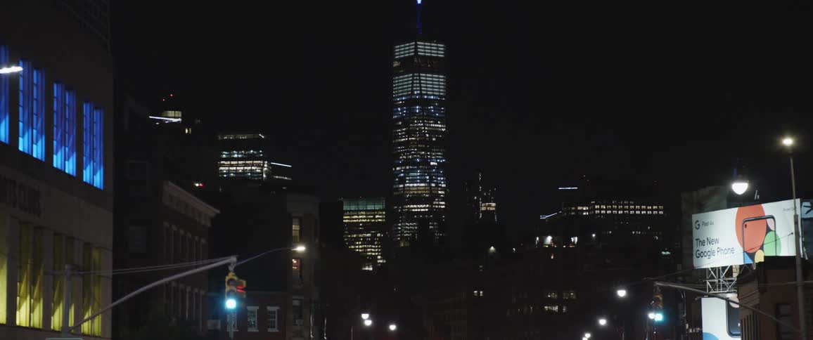 Illuminated skyscraper and high rise buildings seen from vehicle driving down highway at night