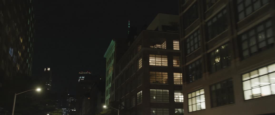 Driving downtown in a city passing buildings traffic lights and street lights at night