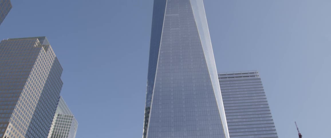 While moving down the street lined with trees the skyscraper comes into view up to the top