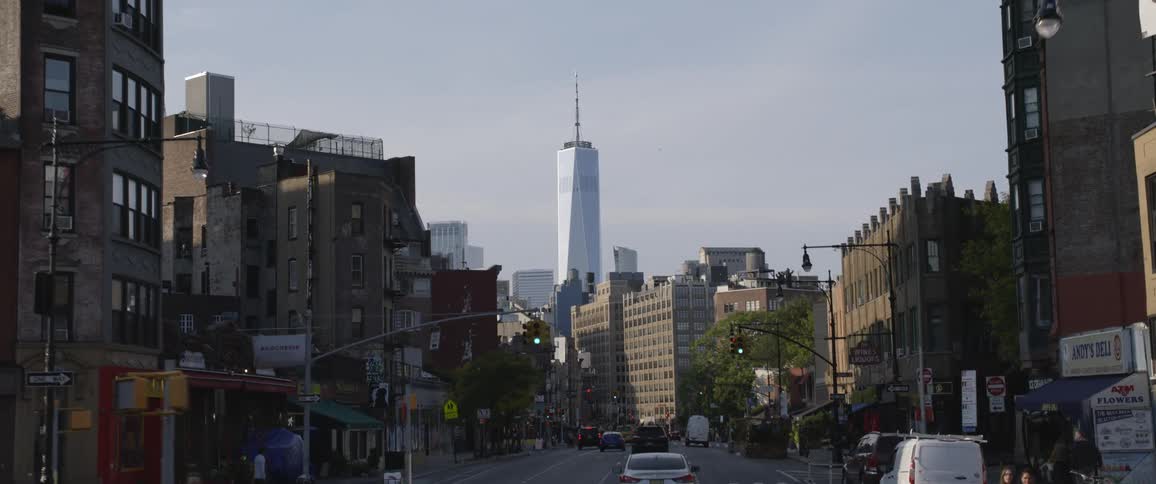 A car traveling on a city street with a tall skyscraper in the distance