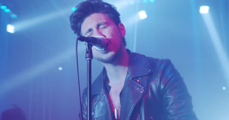 Young male singer singing on the microphone over the stage in a show