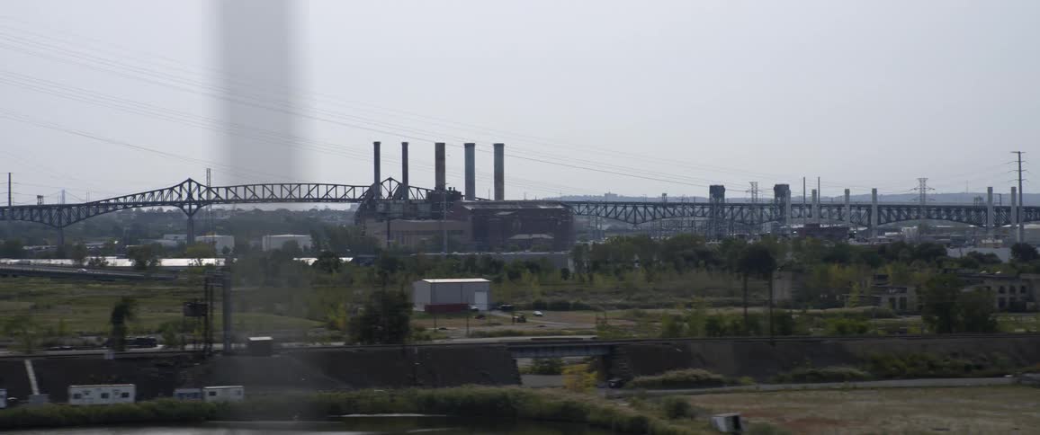 Vehicles driving by a factory on the shore