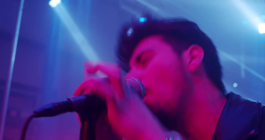 A man sings under bright lights on a stage