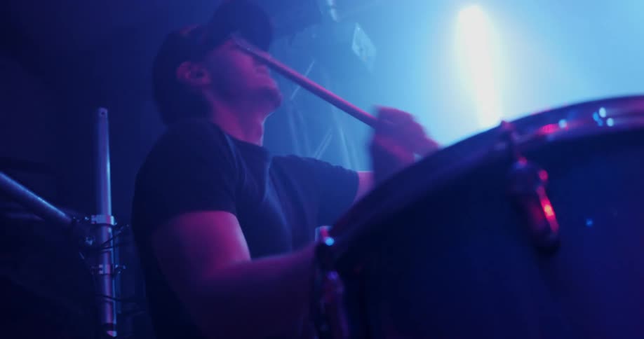 A man is playing drums at a venue