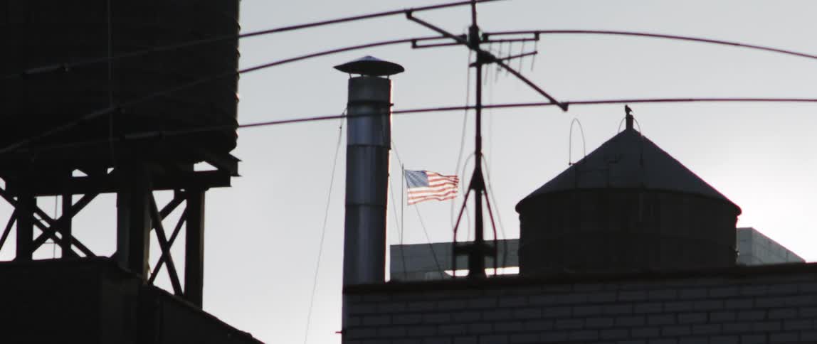 The american flag flapping in the wind in an industrial area