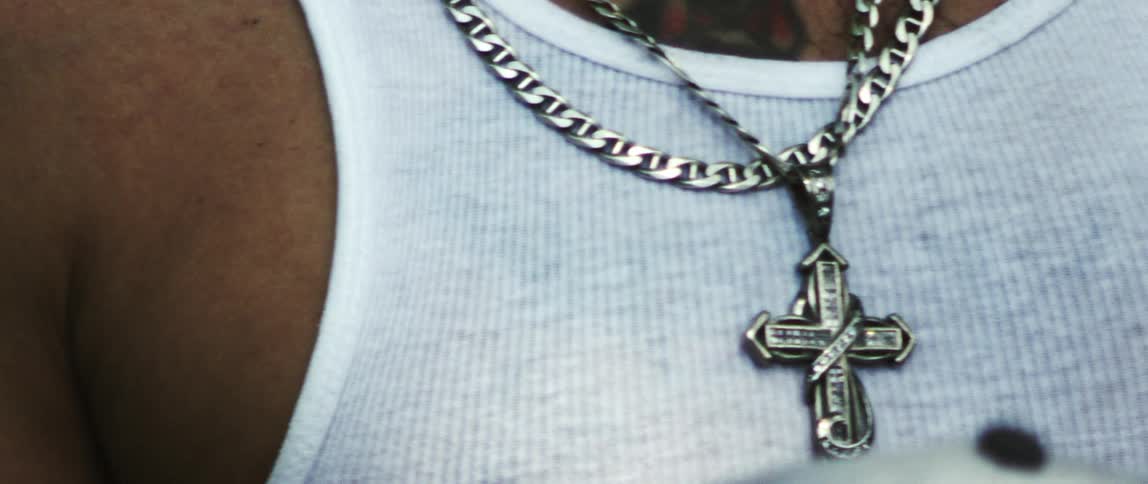 Man wears cross necklace and chain with a wife beater