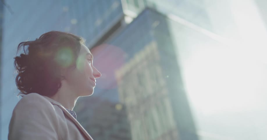 A woman smiles as she stands outside a tall skyscraper