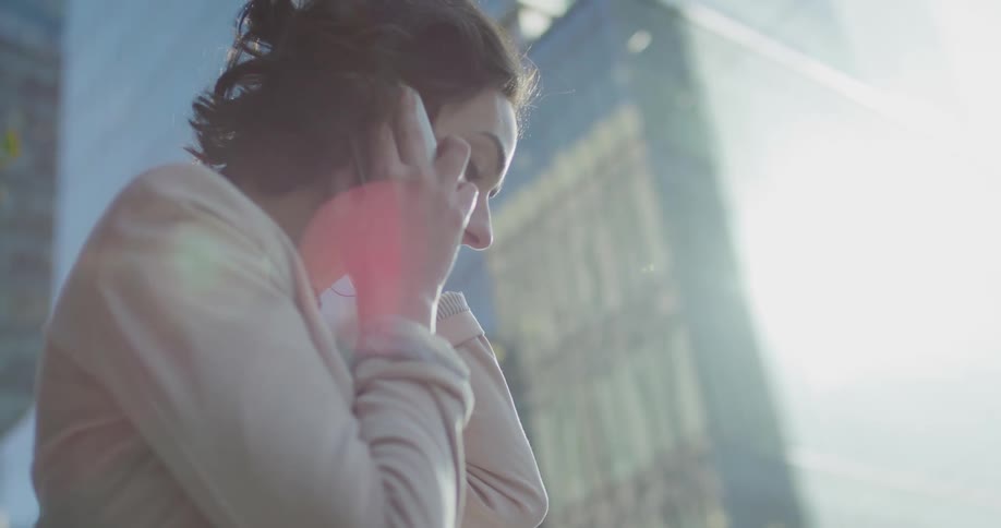 Young woman talking on a smartphone in front of a building in the citys downtown