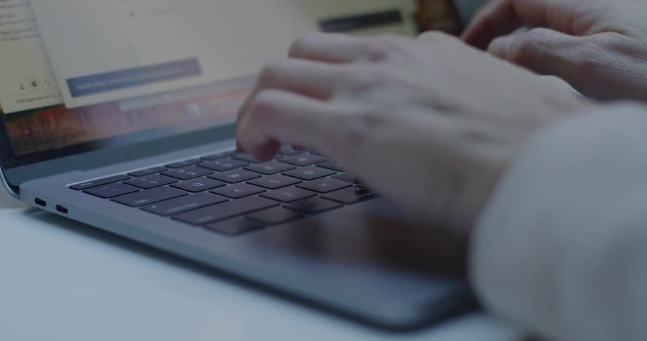 A white person is typing on a laptop keyboard