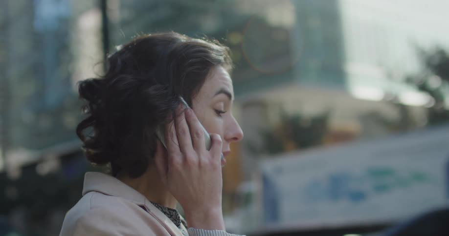 Young woman talking on her smartphone on the citys downtown street at morning