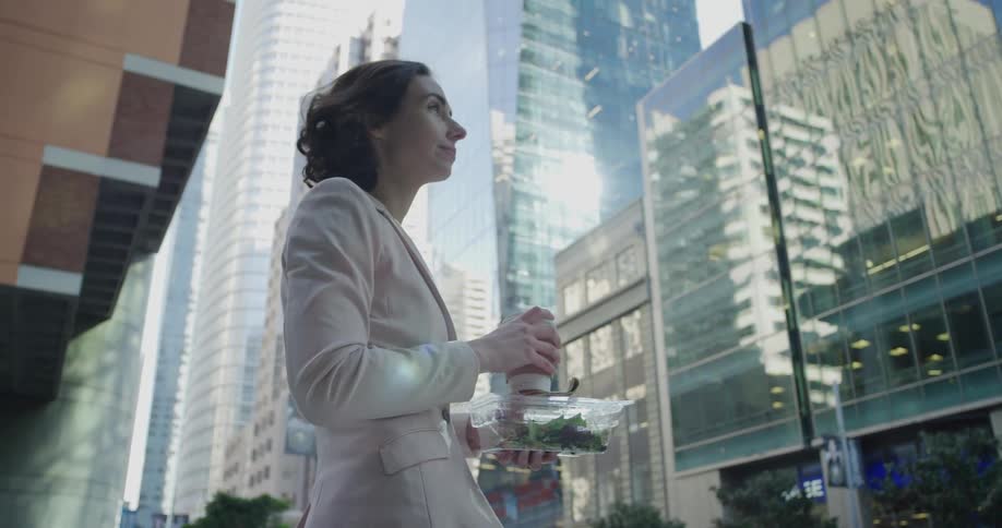 A woman is holding her food on the city street