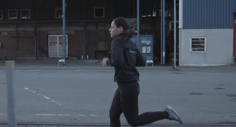 Woman jogging next to a warehouse