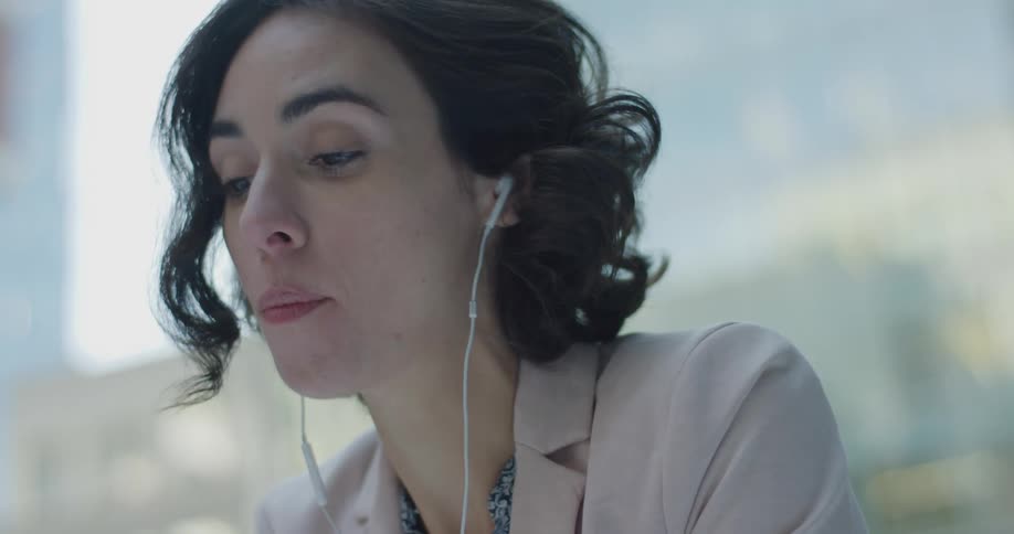 Business woman sitting outside eating salad and drinking coffee while listening to music