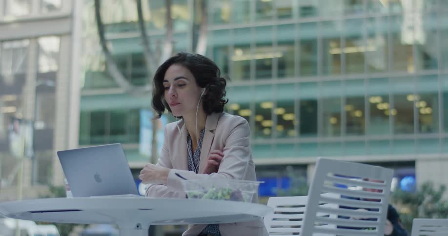 A woman sitting outside a building with a laptop