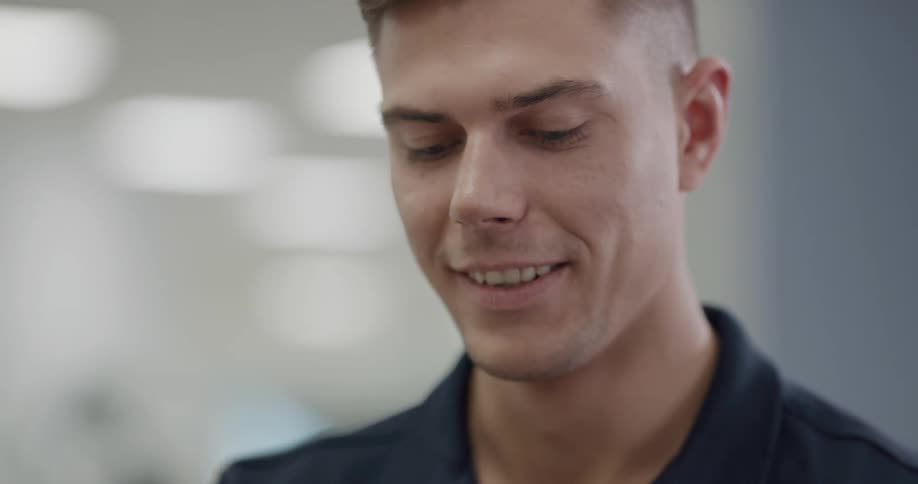 A man wearing a blue shirt smiles while looking down inside