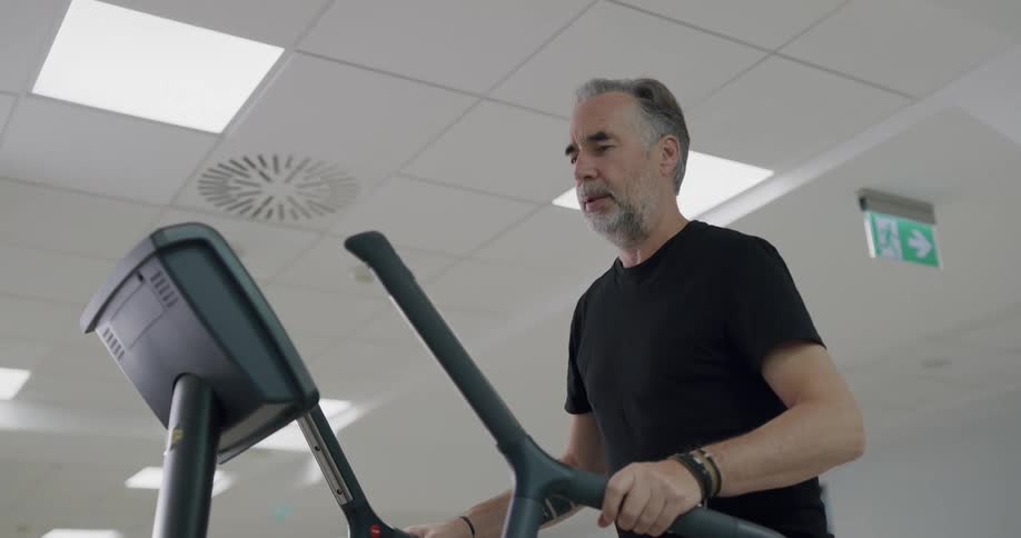 A man wearing a black t shirt exercises on a piece of equipment in a gym