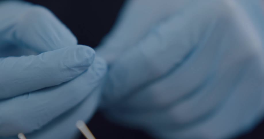 An acupuncturist removes a needle from its sterile packaging to place on a client