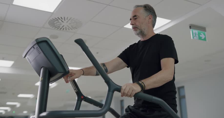 Man climbing on a walking machine inside a gym