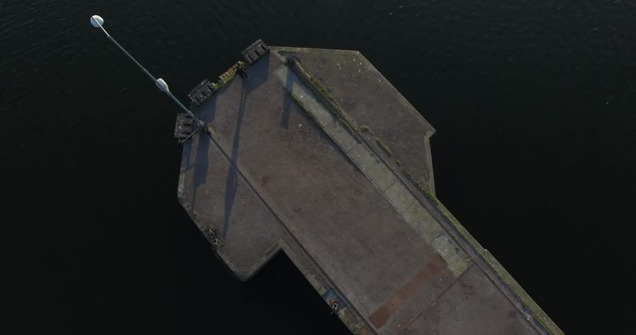 A man stands at the end of a concrete pier