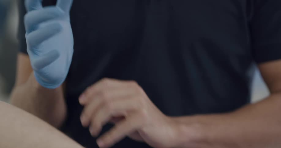 A male nurse puts on blue latex gloves
