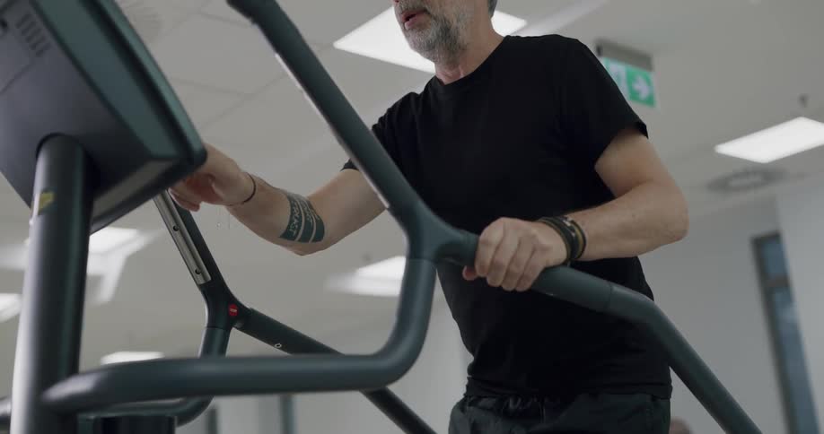 Man walks on stair master and stumbles while working out other men work out in the gym behind them