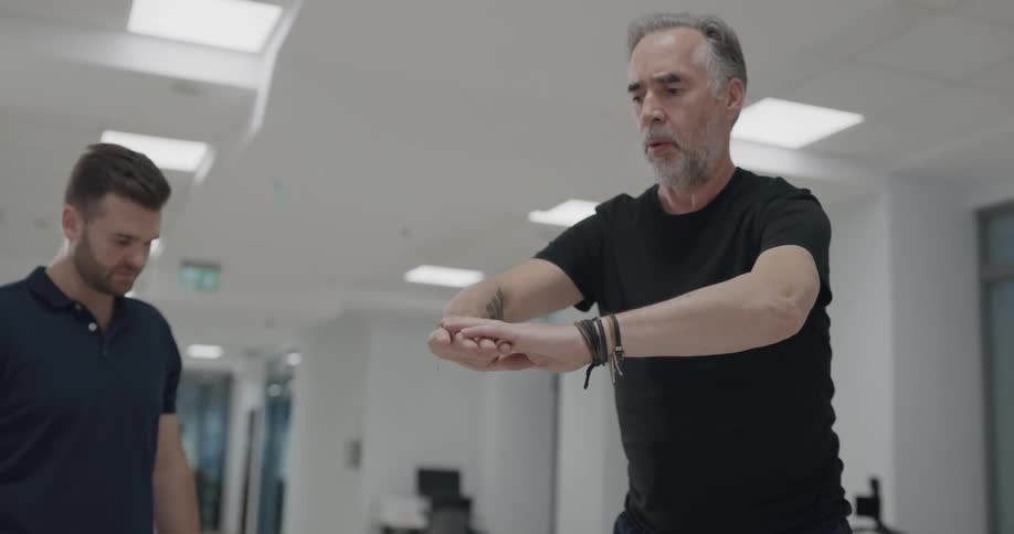 Man squatting and exercising while instructor observes