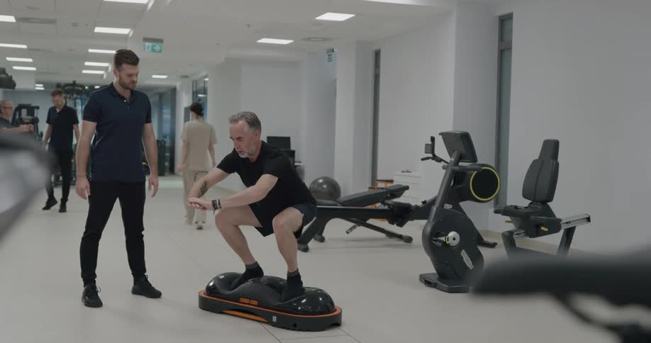 A man instructs a patient on how to do physical therapy exercises