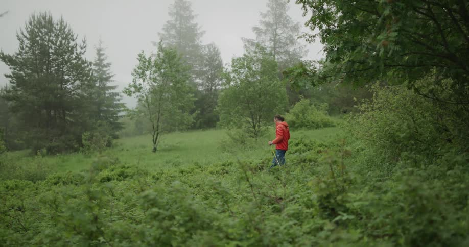 A man uses poles to walk through a grassy area in overcast conditions