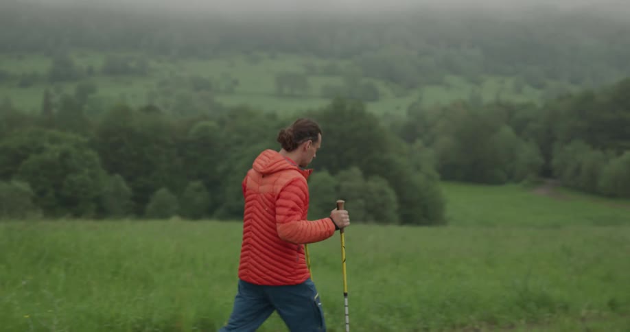 A man uses walking sticks as he hikes down a hill