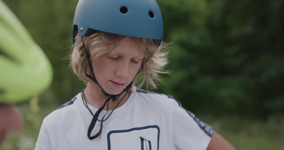 A young boy listens and follows instructions as he works on his bike that is turned upside down