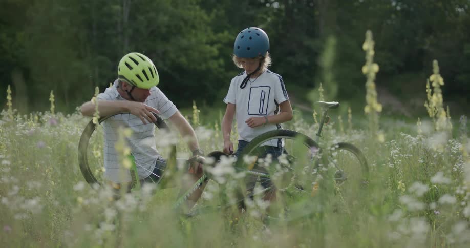 Father and son celebrate as they fix a bicycle outside in a field