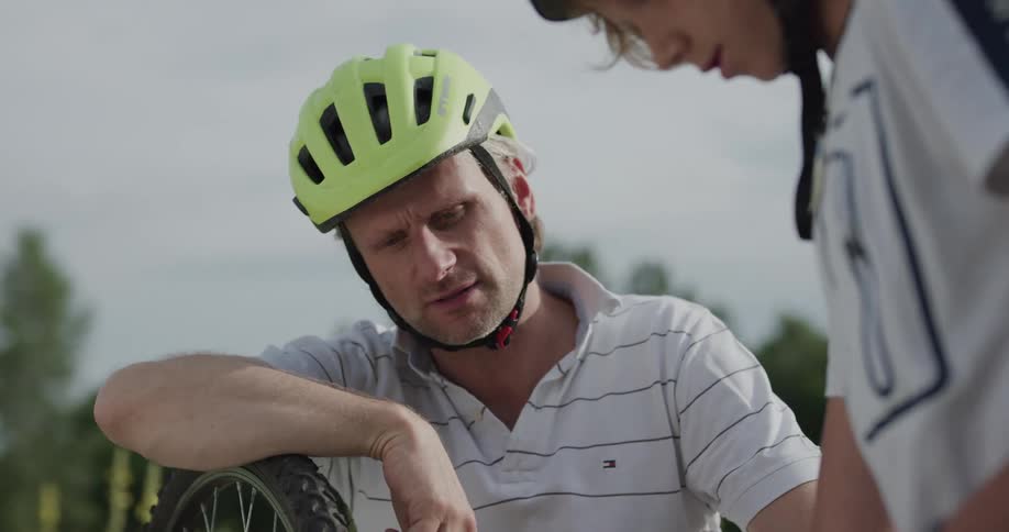 Father teaching son how to repair a bicycle on a grass field