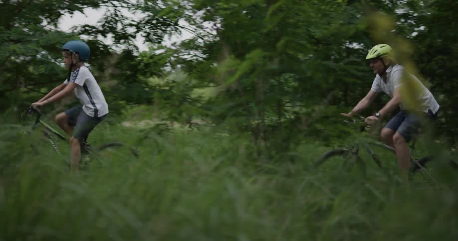 Father and son ride bikes on a hill in nature