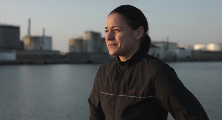 A woman is standing near near the water at sunset