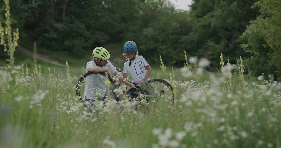 Dad and son stop in a field to fix a bicycle