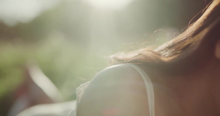 Young woman laying on a blanket over the grass outdoors at sunset
